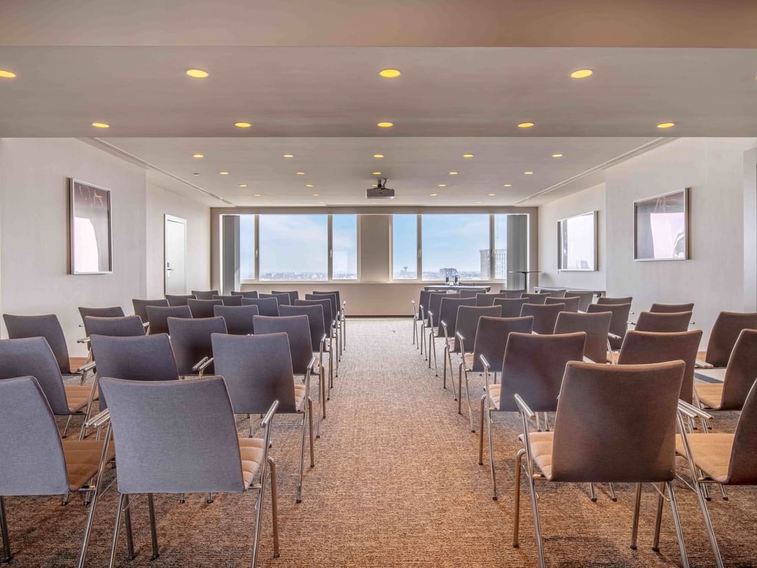 Meet 26 One Meeting room with rows of chairs facing a projector screen at The Hotel Brussels