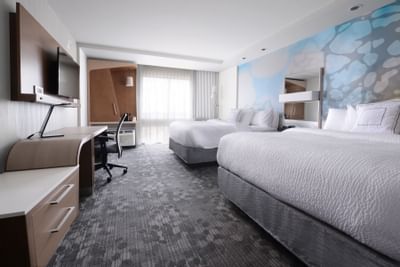 room with two queen beds, work desk and television on wall