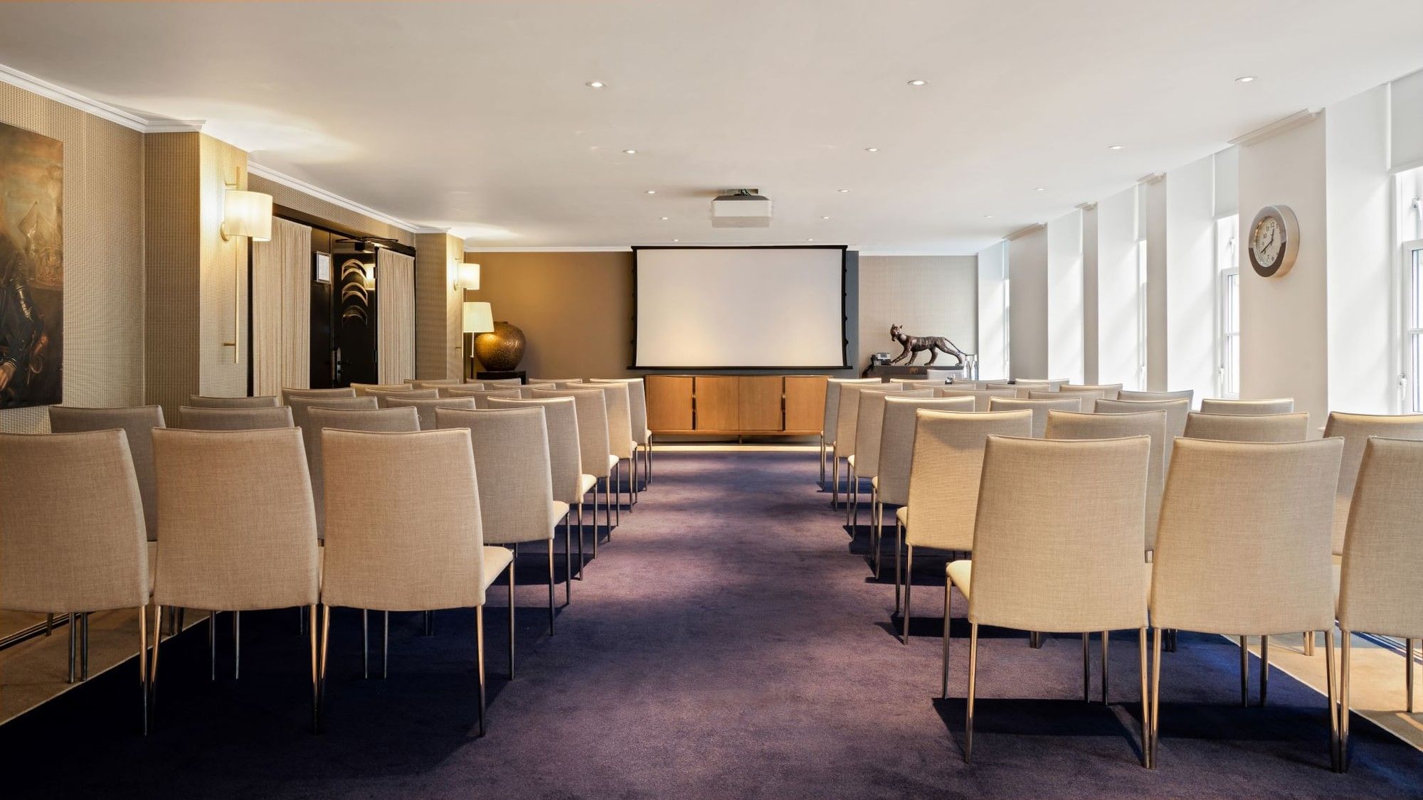 Event room with theater seating and a projector screen for presentations at The May Fair Hotel