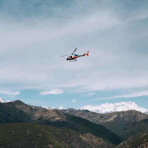 A helicopter flying over a mountain range, Falkensteiner Hotels