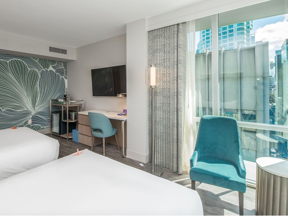 Two queen beds, desk, chair, and cityscape view.