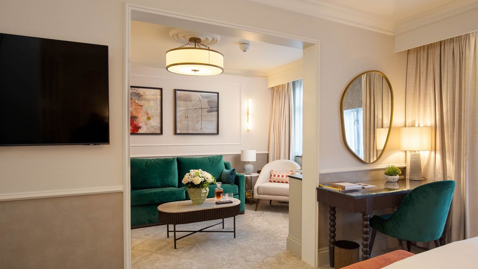 A luxurious living area with a green couch, desk, and modern decor at The Capital Hotel.