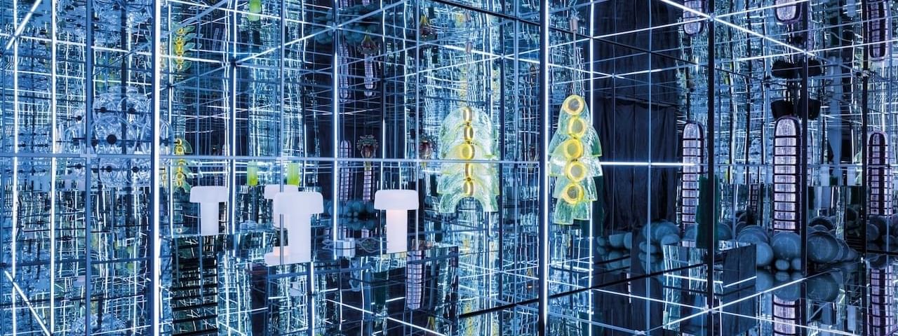 Futuristic mirrored room with bright neon lights and various glass sculptures at Almanac X Alcron Prague