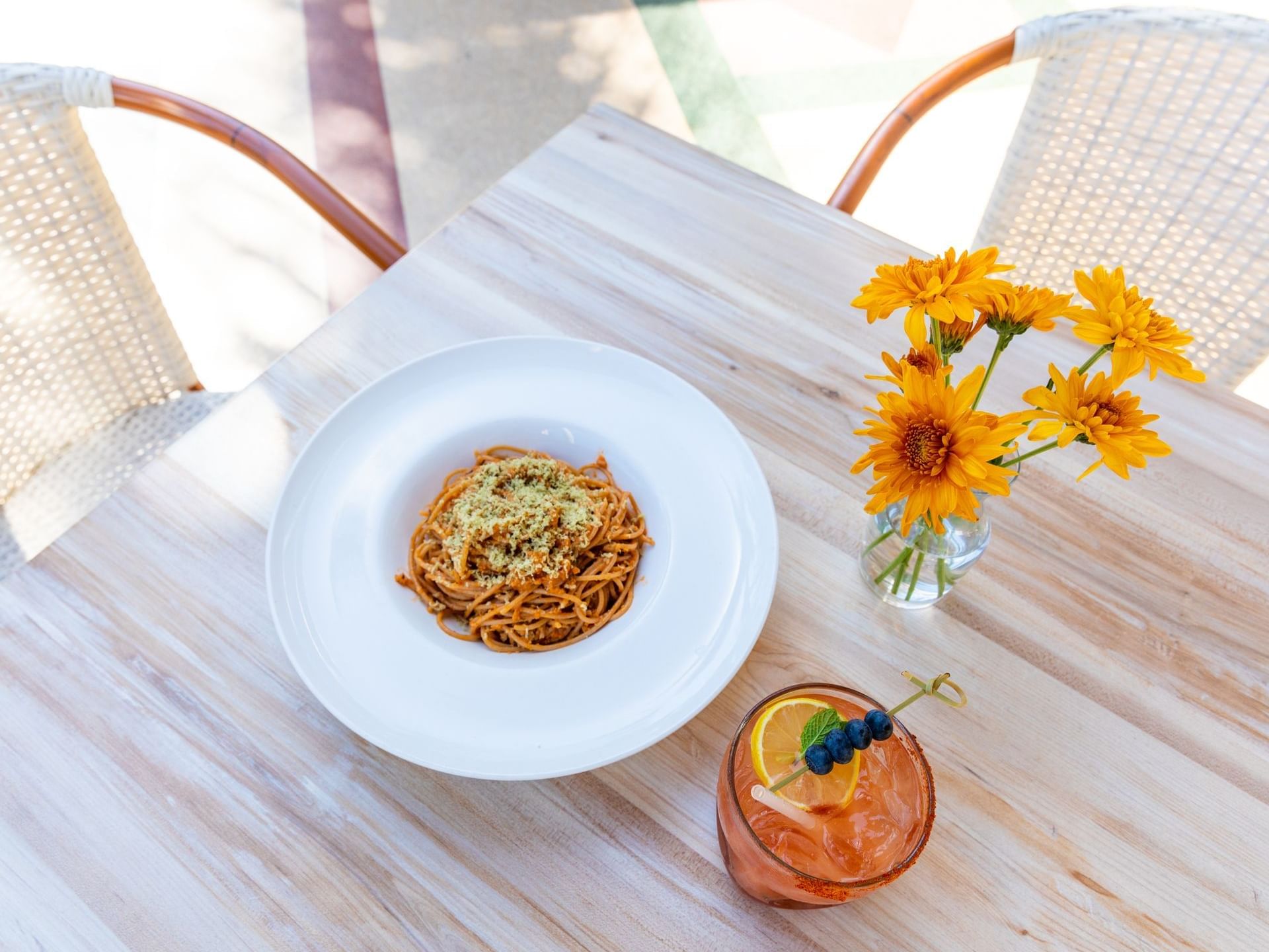 Top shot of a plate of pasta with a cocktail at Crest Hotel