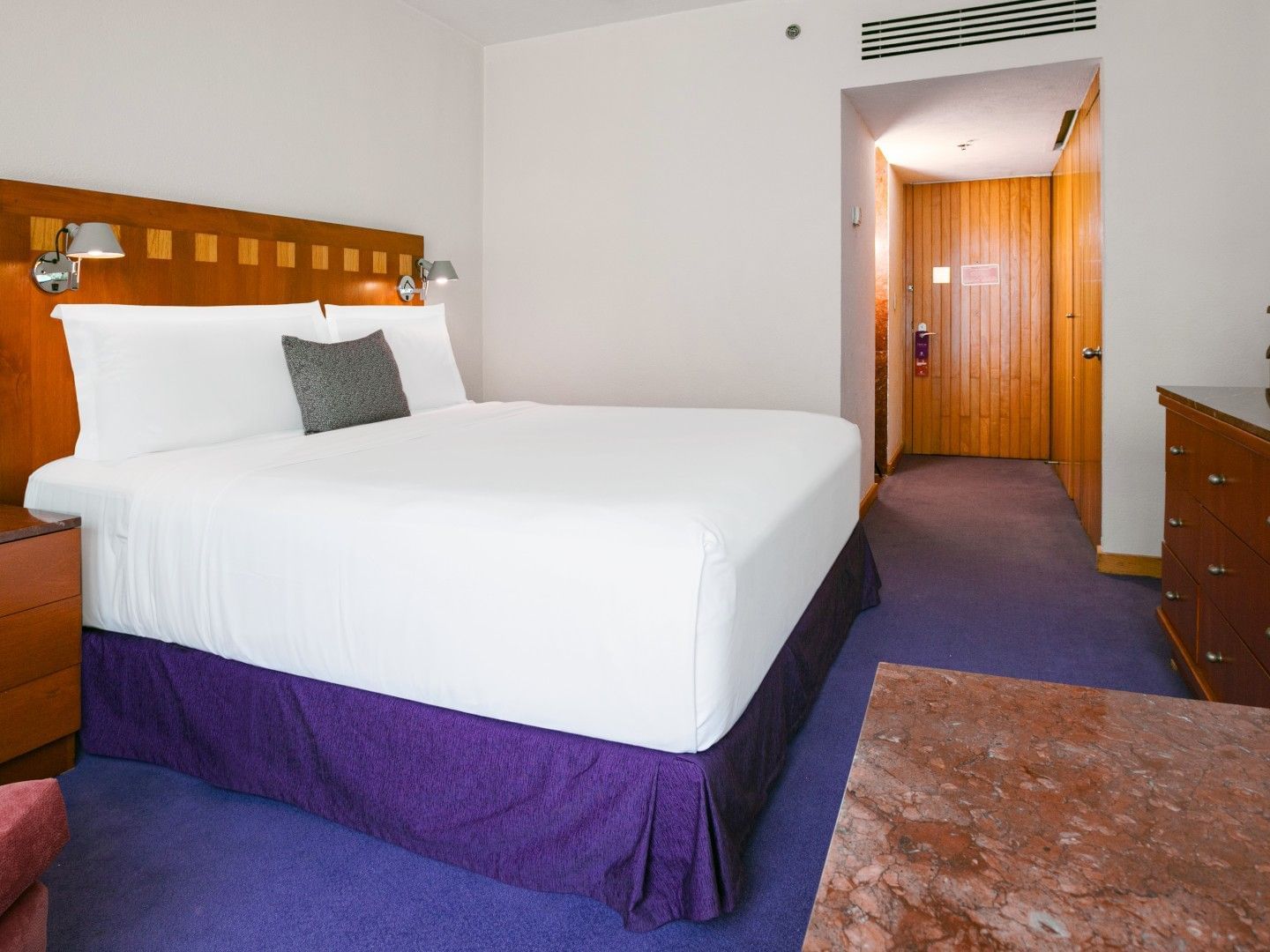 King Deluxe room featuring a king bed with purple skirt and marble-top furniture at Camino Real Polanco Mexico
