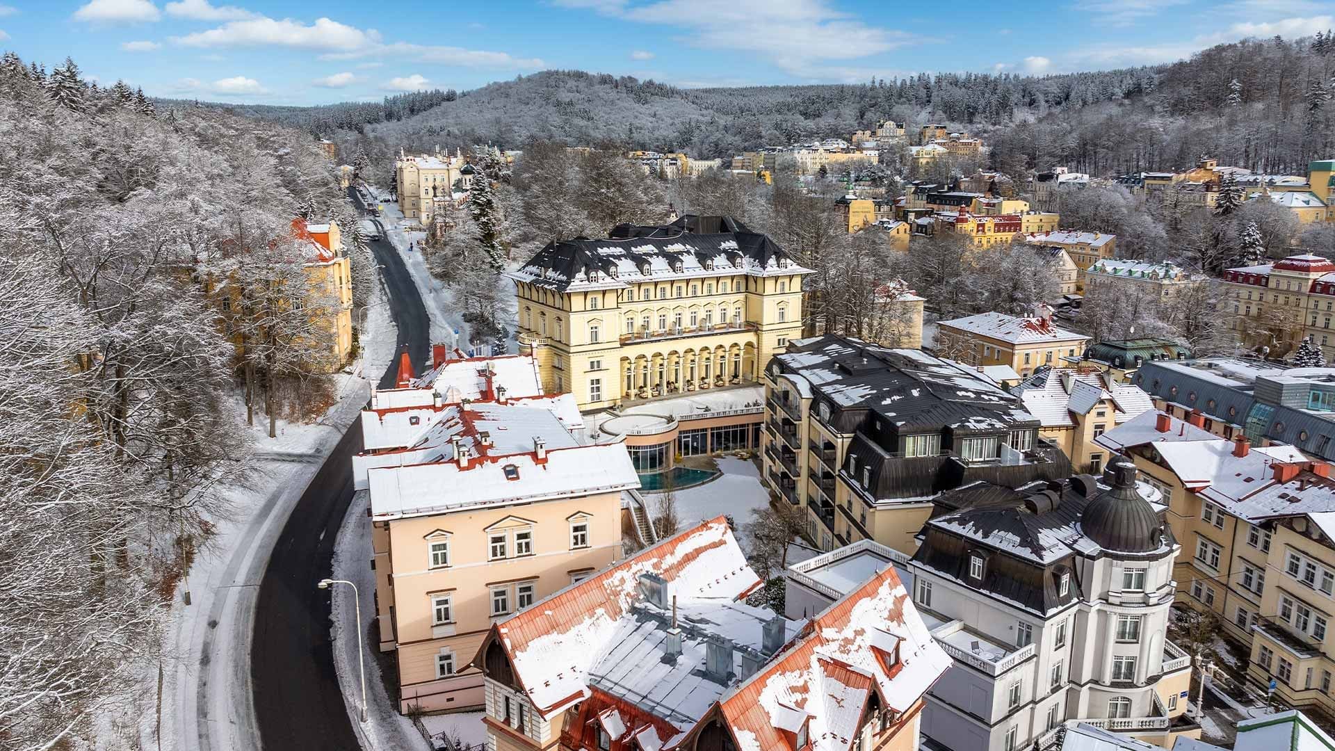 Luftaufnahme einer schneebedeckten Stadt mit Gebäuden und Bäumen im Winter.