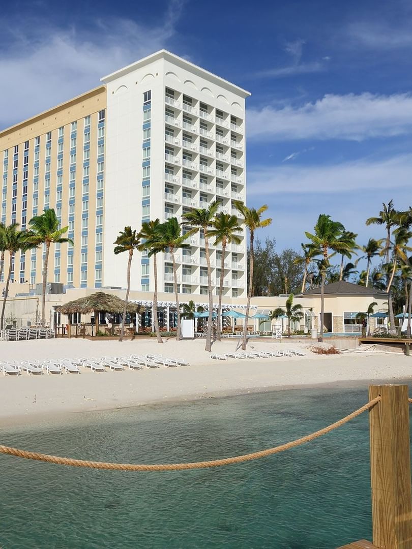 Warwick Paradise Island Bahamas Hotel by a sandy beach under a blue sky, surrounded by white loungers
