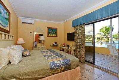 Bed beside sliding glass door opening to a private terrace in Deluxe Villa King Bed Ocean View at Lindbergh Bay Hotel