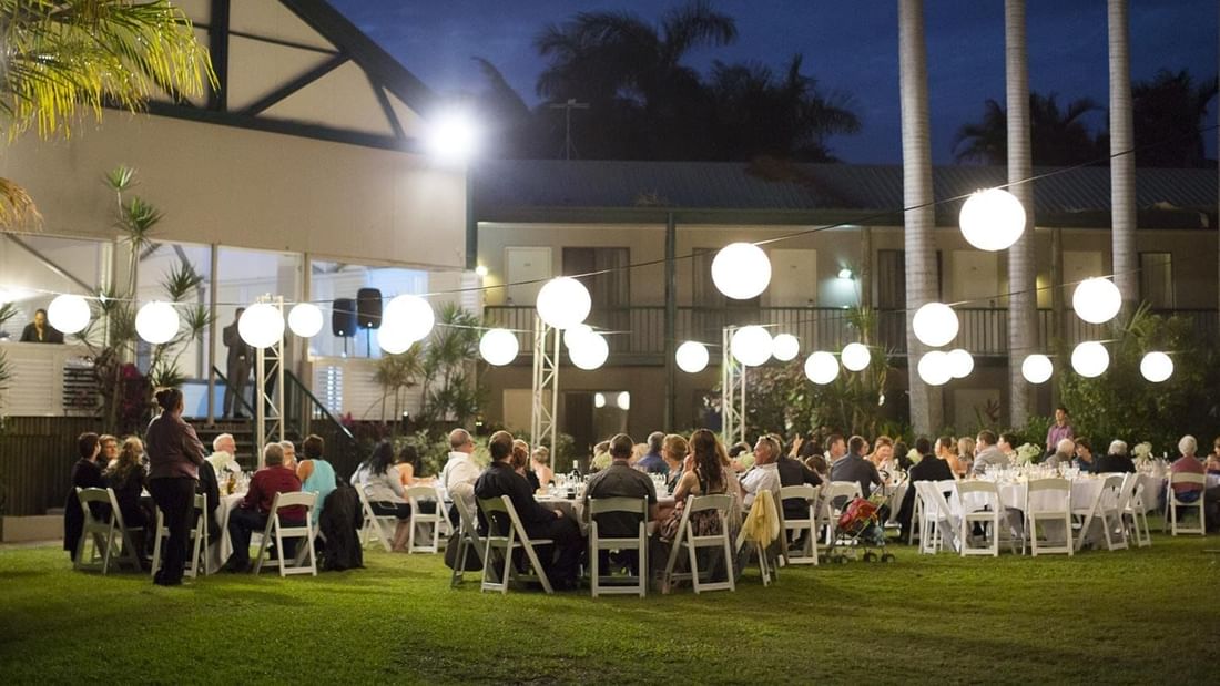 Beautiful outdoor evening event with guests dining under glowing round lanterns in Receptions at Mercure Hotel Townsville