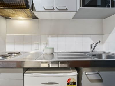 Modern kitchen with stove, sink, and compact fridge in Student Living Auckland - Beach.