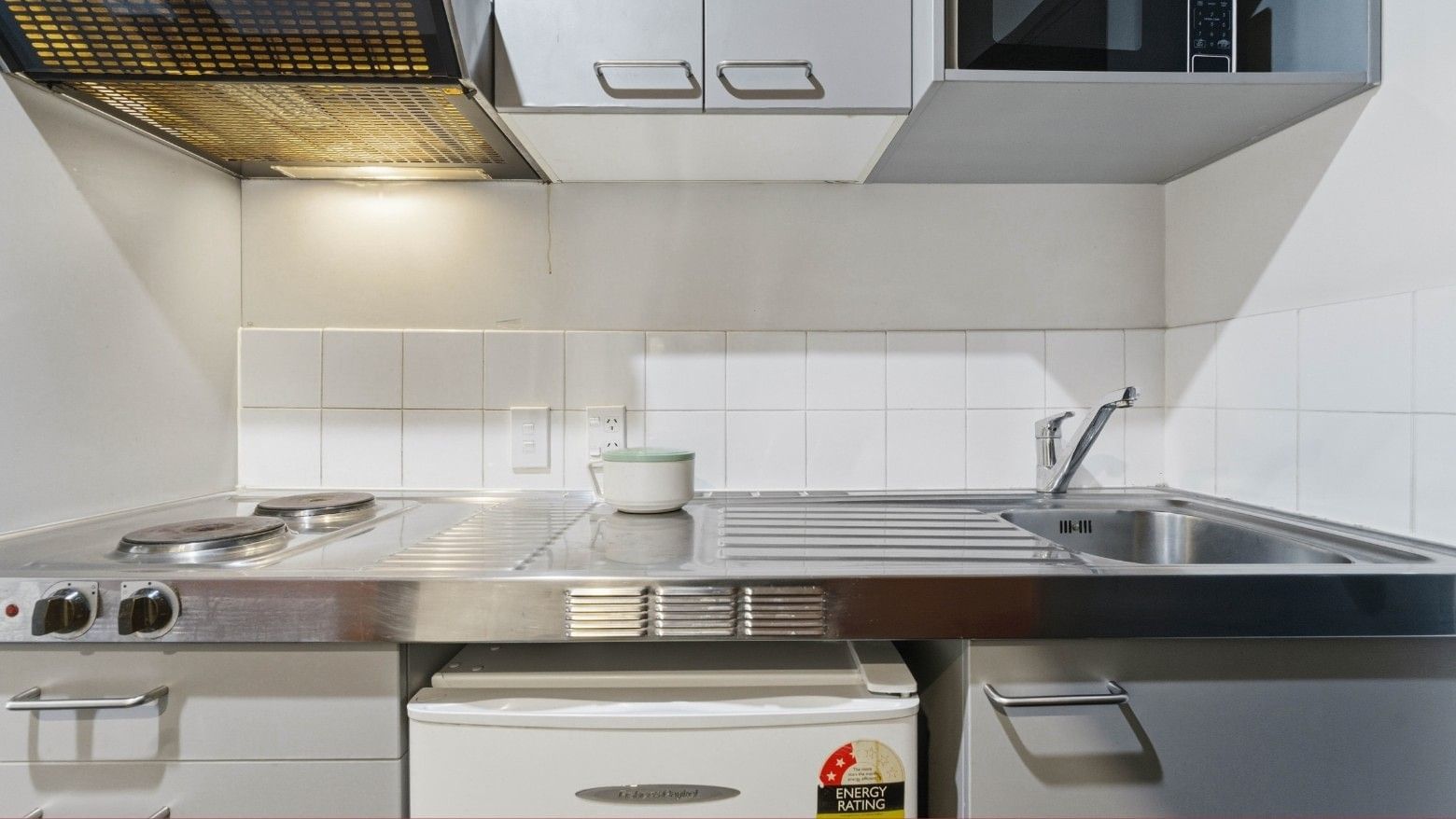 Modern kitchen with stove, sink, and refrigerator at Student Living Auckland - Beach.