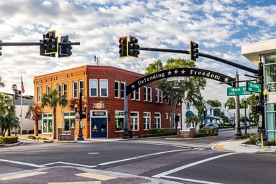 Street view of a historic red-brick visitor center with a Defending Freedom arch near The J Hotel