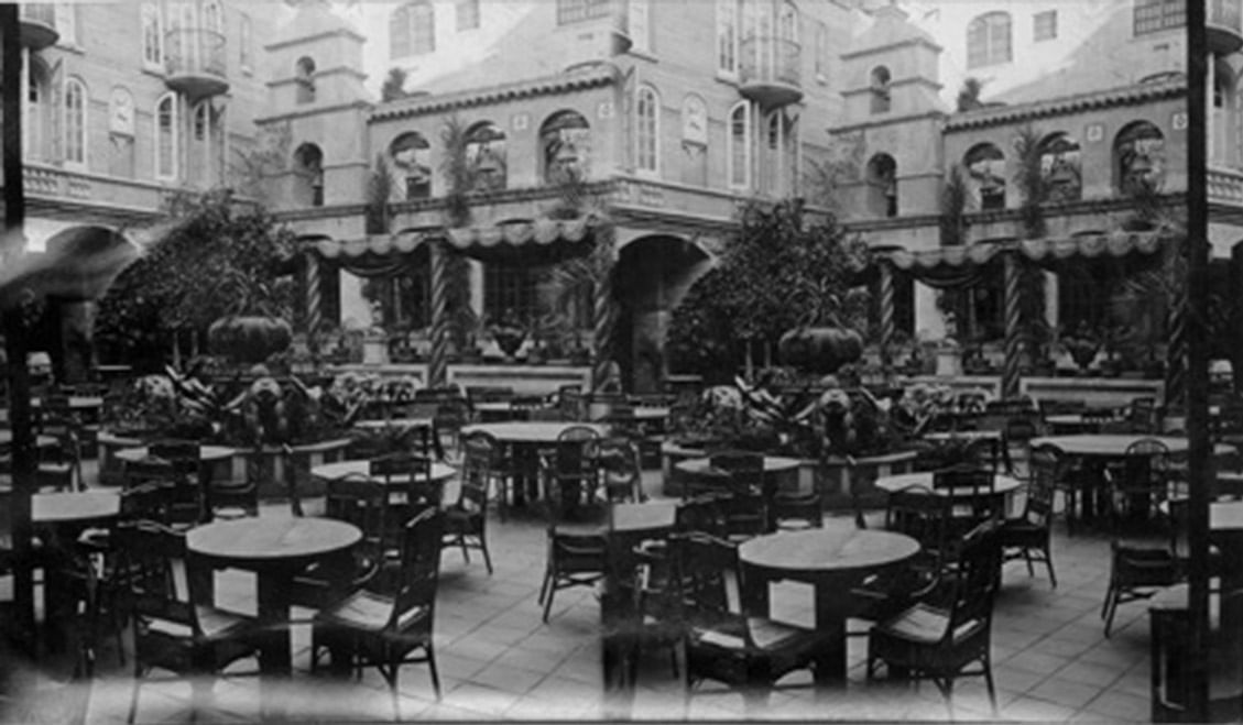 vintage image of exterior patio of Mission Inn with tables and c