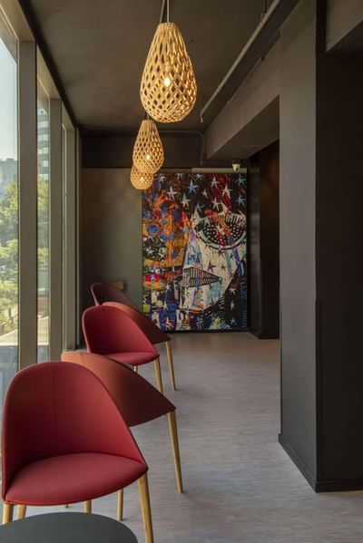 Modern interior at Hotel Nodo with red chairs, wood pendant lights, and an abstract mural on a dark wall