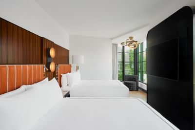 TV-facing bed with modern interior in 2 Queen Beds Deluxe Corner Room at Godfrey Hotel Detroit