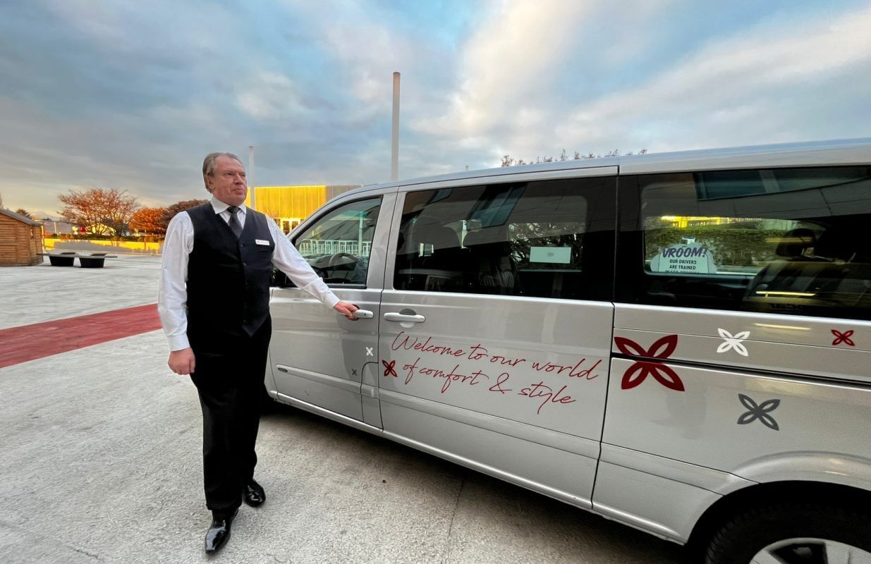 Man standing beside a shuttle van displaying the Starling Hotel Lausanne sign