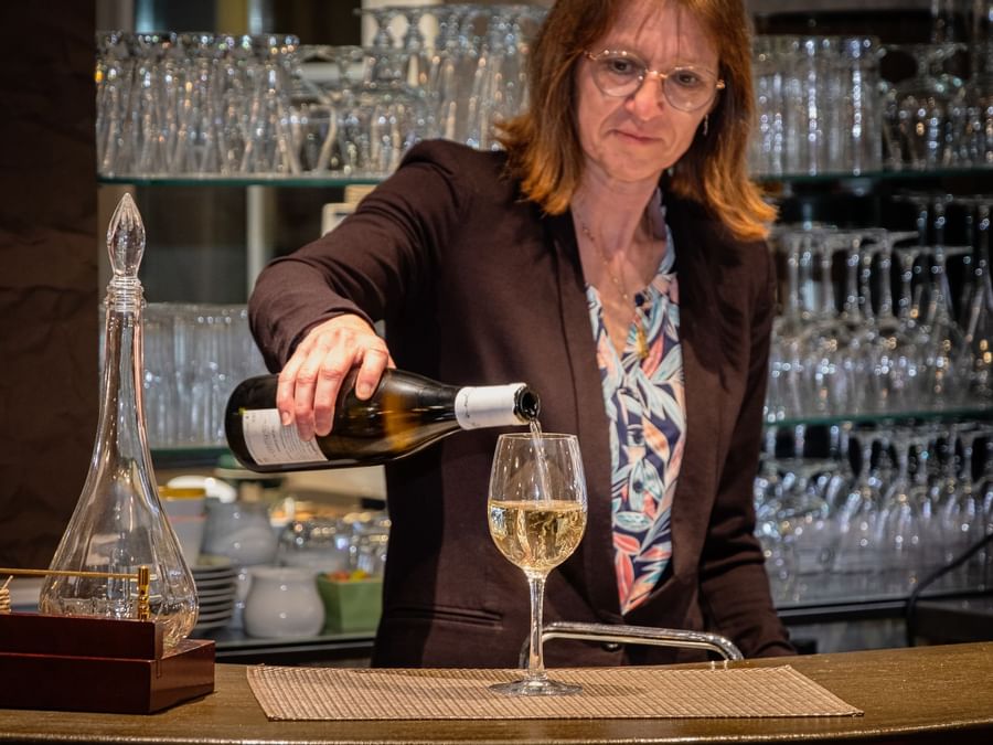 A woman pouring champagne into a glass at The Originals Hotels