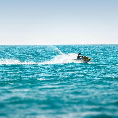 Man jet skiing on the sea near Falkensteiner Hotels