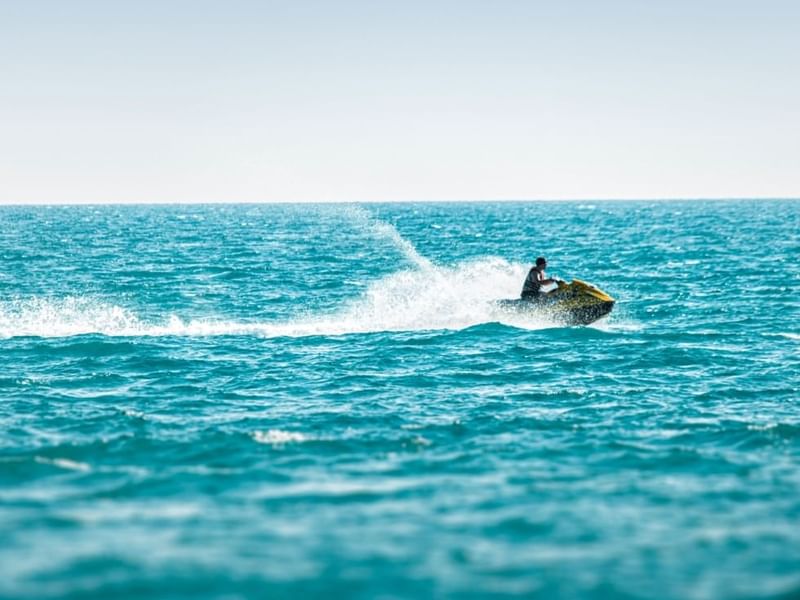 Man jet skiing on the sea near Falkensteiner Hotels