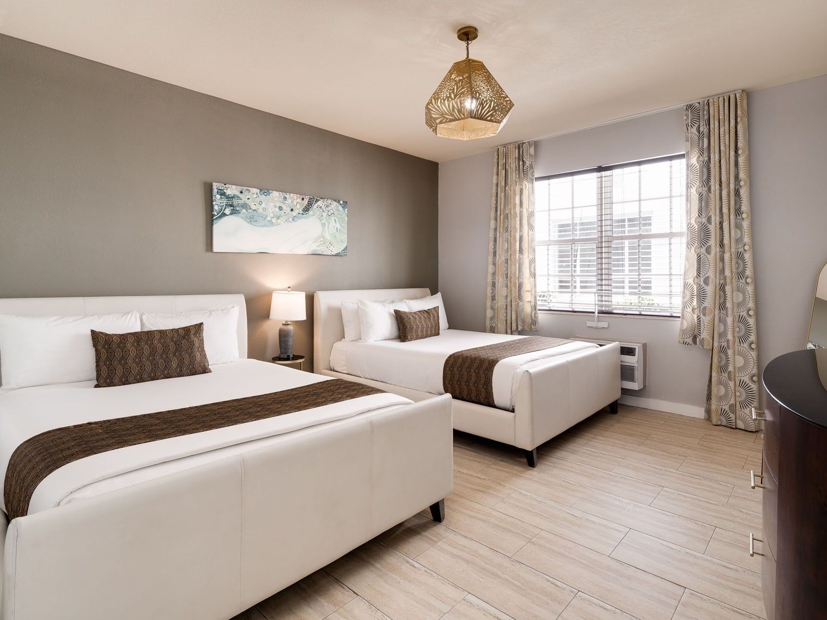 Courtyard View One Bedroom Double Queen Suite with two white queen beds with brown accents at Tradewinds Apartment Hotel