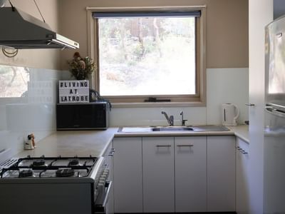 A fully equipped kitchen with white appliances and cabinets at La Trobe University - Villas.