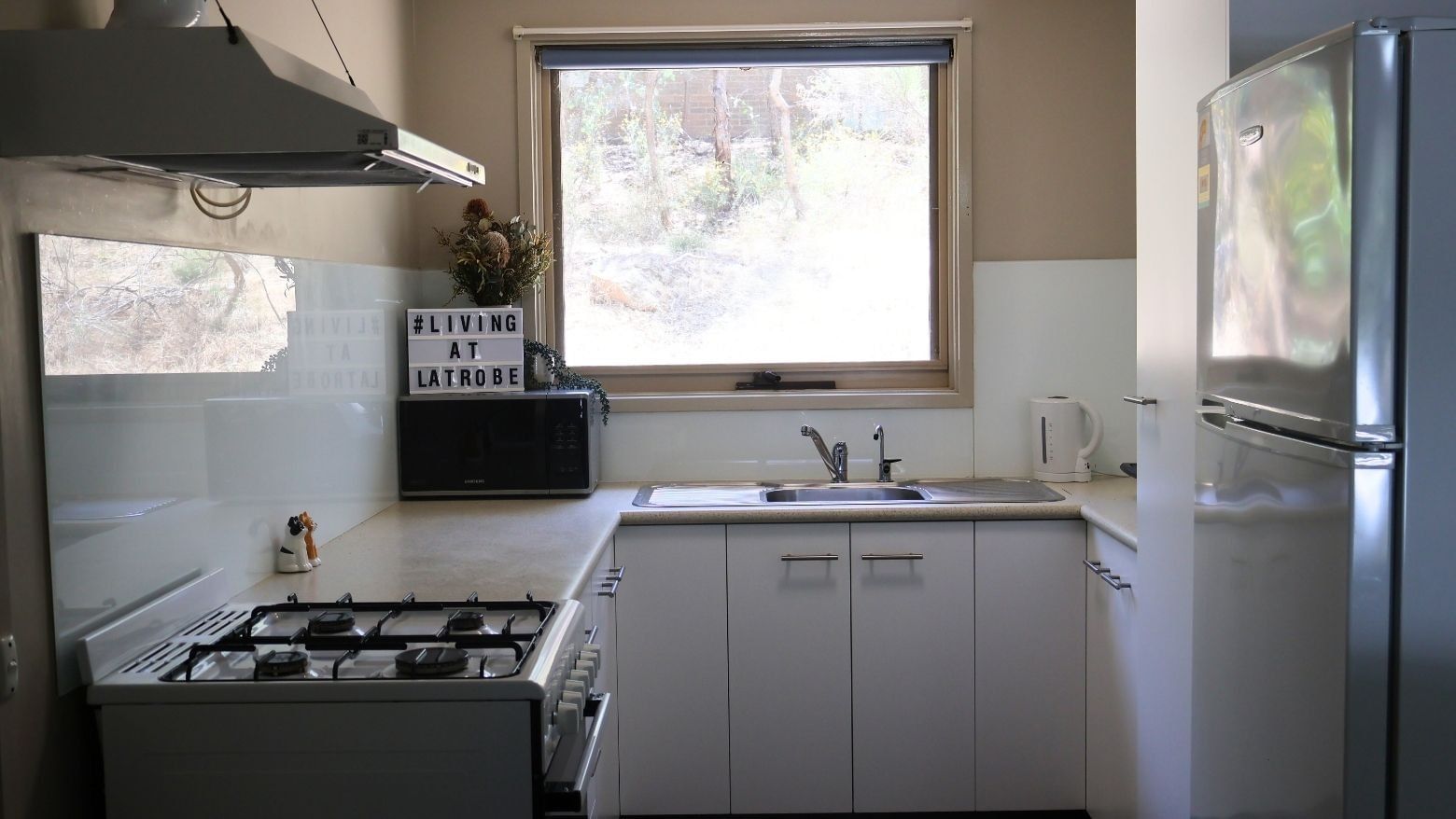 A fully equipped kitchen with white appliances and cabinets at La Trobe University - Villas.