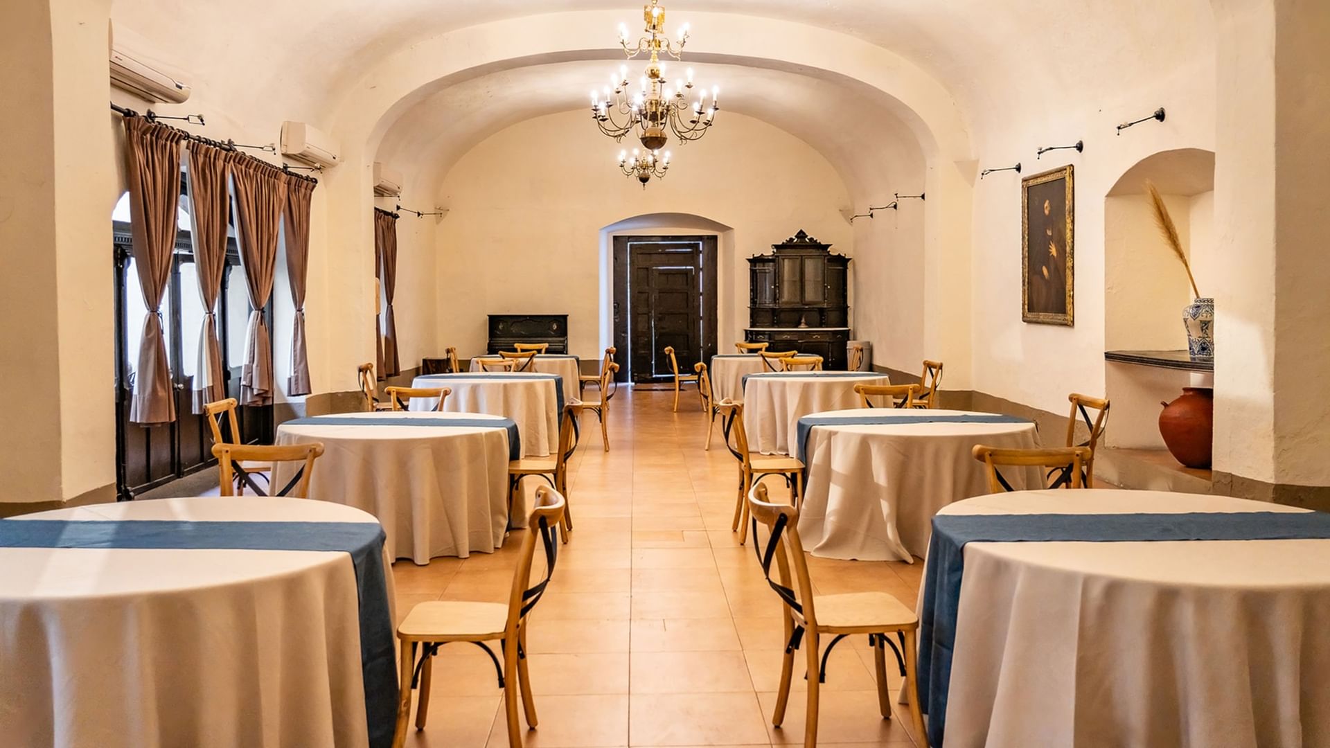 Elegantly arranged dining area with chandeliers and artwork in 5 de Mayo at Quinta Real Puebla, Heroica Puebla de Zaragoza.