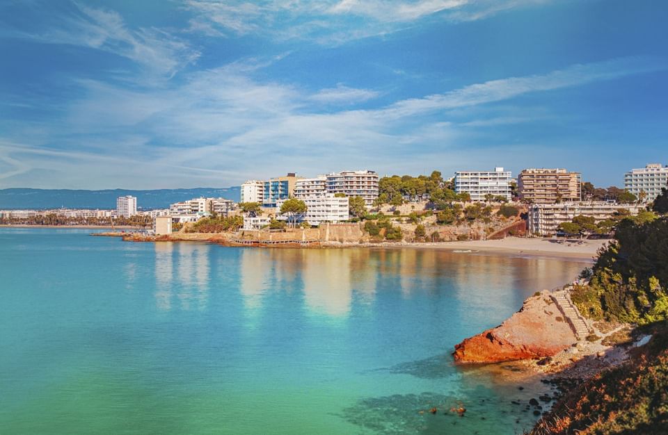 A scenic coastal view with sandy beach, turquoise waters near Hotel Piramide Salou