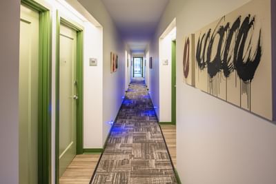 Modern hallway, featuring abstract purple and red artwork placed on the walls by guest room doors at Hotel Keen