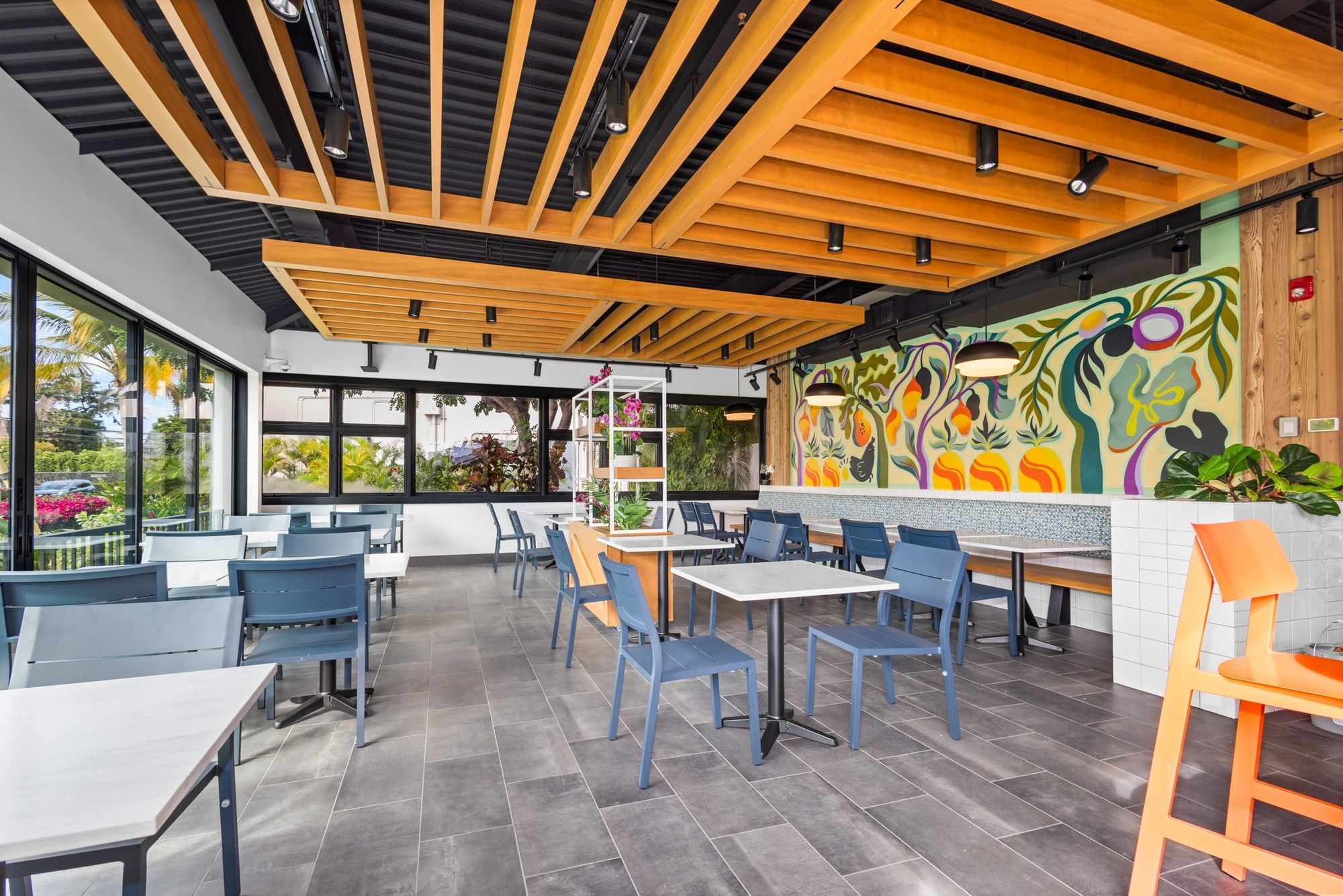 a dining area with tables and chairs, a mural on the wall, and large windows