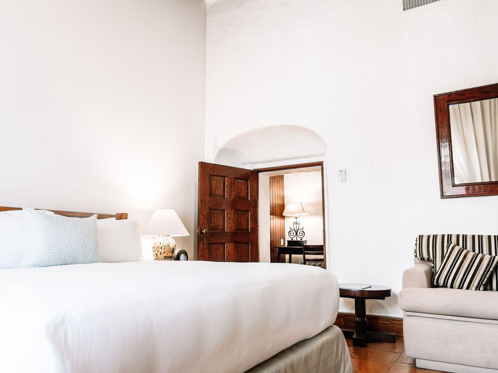Plush seating area and nightstand by the cozy bed in the King Governor Suite at Quinta Real Oaxaca