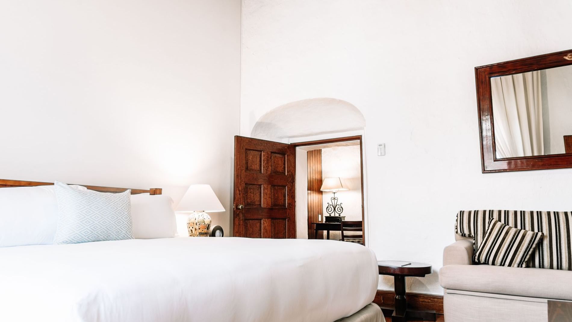 Plush seating area and nightstand by the cozy bed in the King Governor Suite at Quinta Real Oaxaca