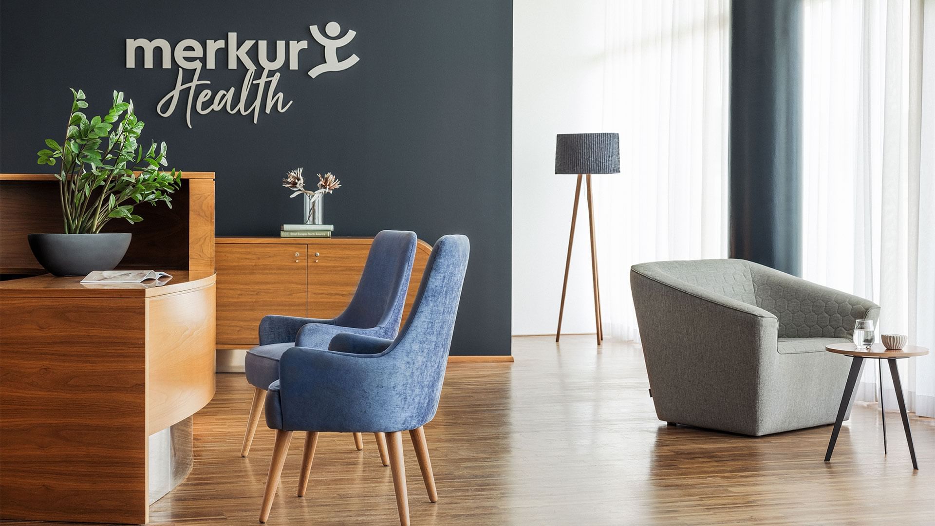 Reception area with two blue chairs, wooden desk, gray armchair, and 