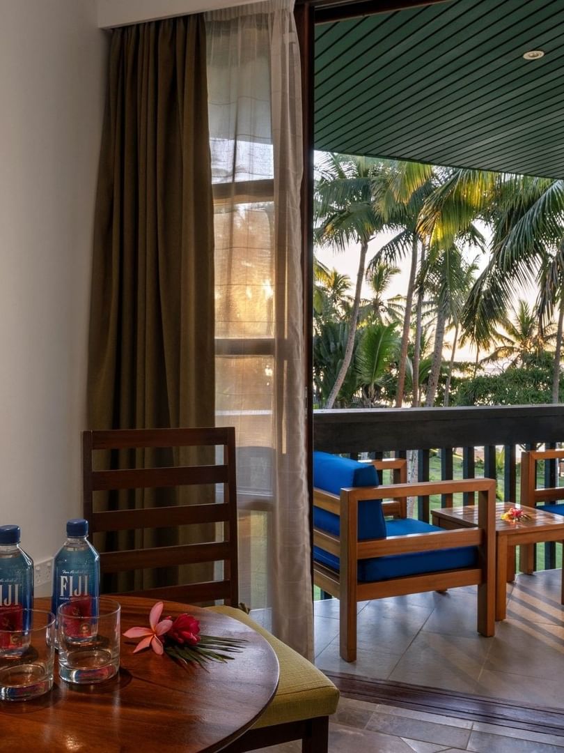 Wooden table with water bottles by a chair under a framed art piece in Warwick Deluxe Rooms at Warwick Fiji Resort and Spa