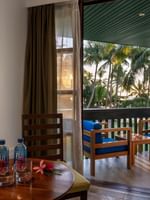 Wooden table with water bottles by a chair under a framed art piece in Warwick Deluxe Rooms at Warwick Fiji Resort and Spa