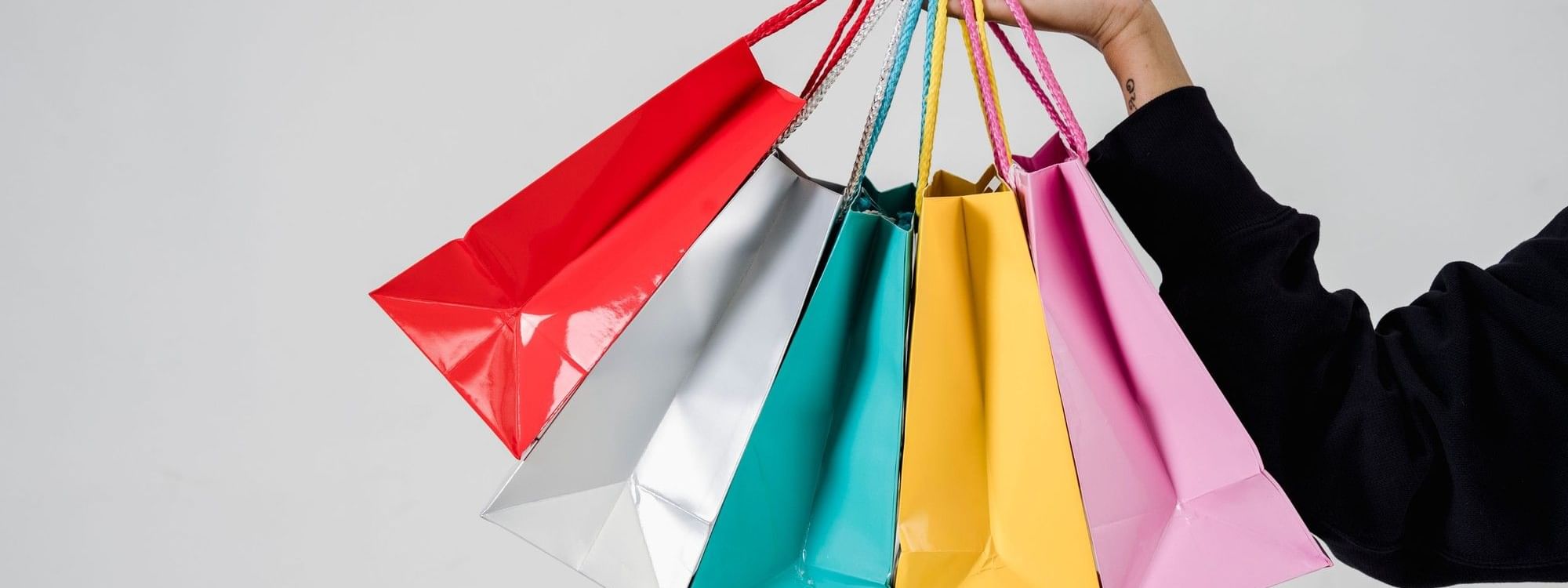 Hand holding several colorful shopping bags at a shop near Novotel Sydney Olympic Park