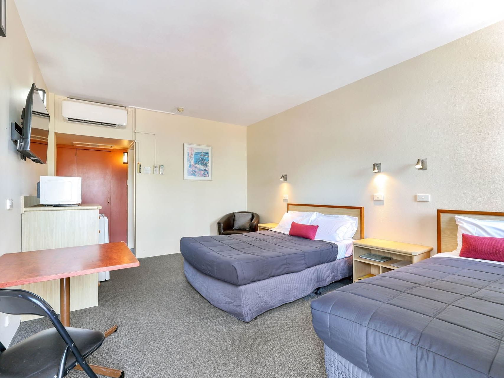 Work desk & TV facing the beds in Standard Twin Room with carpeted floors at Darwin Poinciana Inn