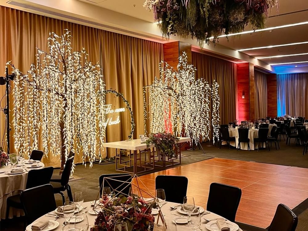 Elegant Salón San Luis with illuminated faux trees and round dining tables at Fiesta Americana San Luis Potosi