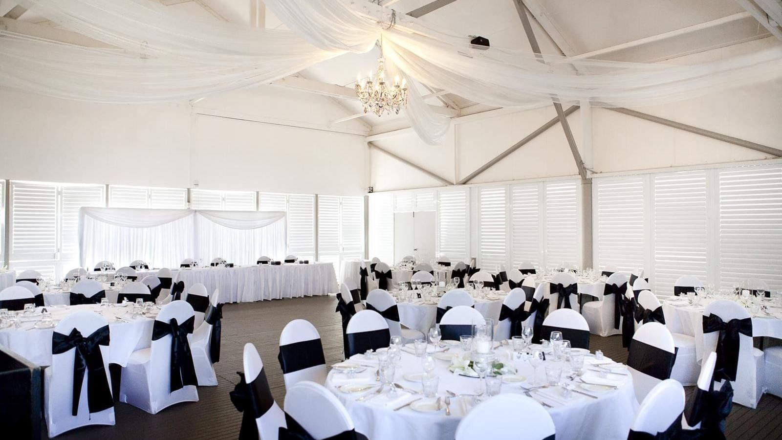 Wedding hall with round tables, soft drapery, and a chandelier at Mercure Hotel Townsville