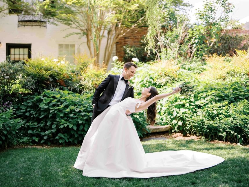Bride and groom dancing in a garden with lush greenery at The Clifton Hotel in Charlottesville, VA.