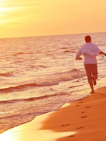 Couple holding hands while running along the shoreline during a golden tropical sunse near TokaToka Resort Nadi Fiji