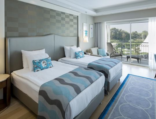Two beds and balcony in the Family Suite Garden at Titanic Deluxe Golf Belek, Antalya.
