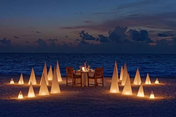 A beach setting for a romantic dinner at night, with a table near Grand Park Kodhipparu, Maldives