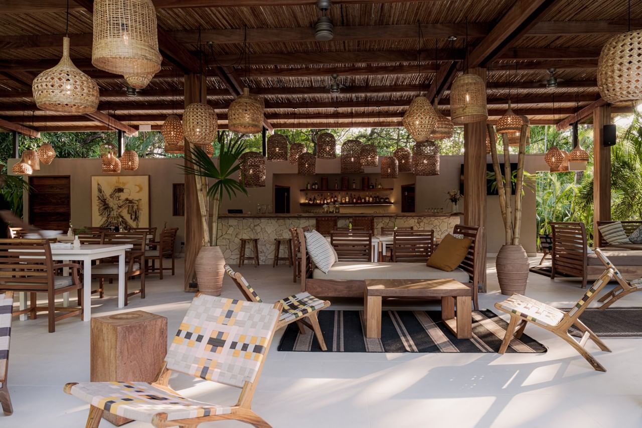 Elegant open-air lounge featuring woven pendant lights and modern wooden furniture at Cala Luna Boutique Hotel
