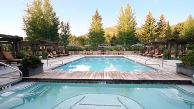 Outdoor pool surrounded by lounge chairs set against a mountain backdrop at Hotel Park City Autograph Collection