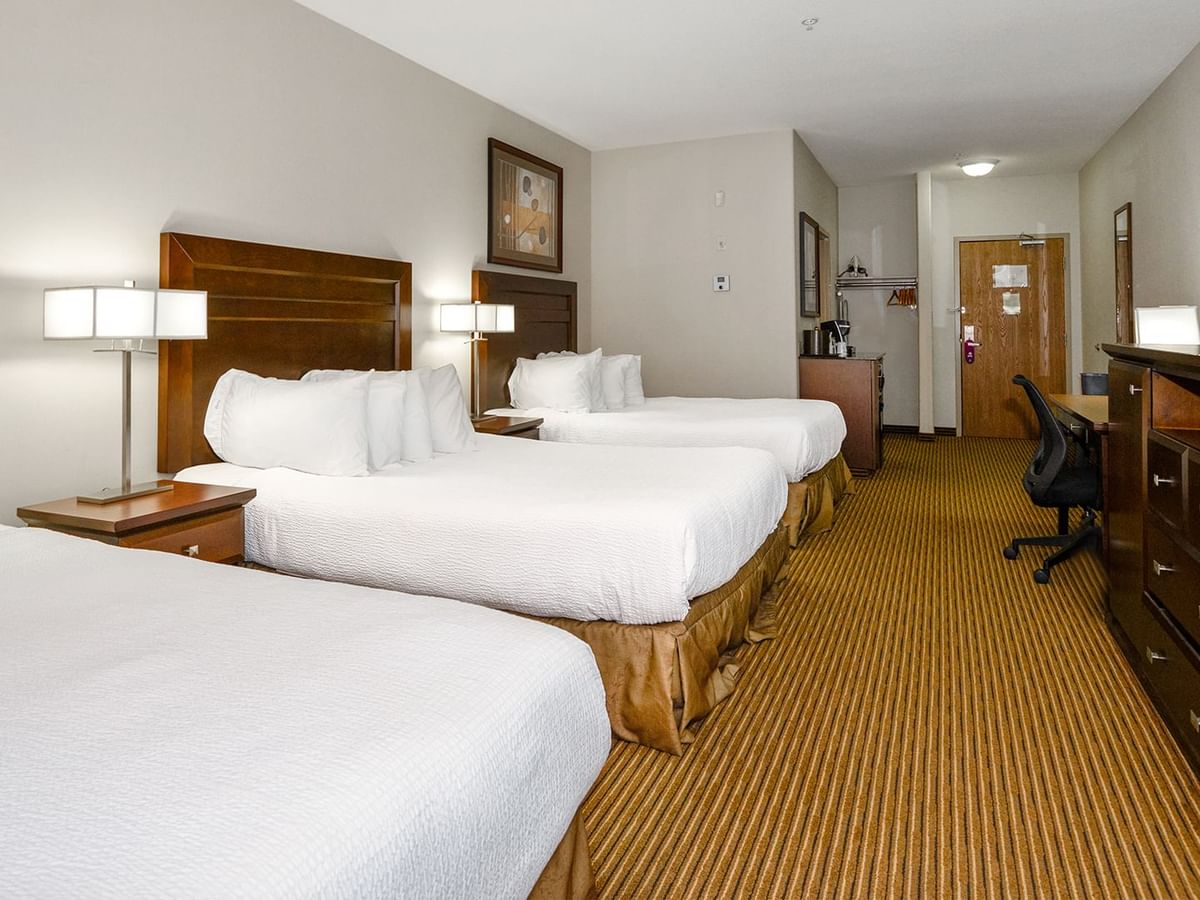 Hotel room with three queen beds, microwave, TV, work desk and coffee machine