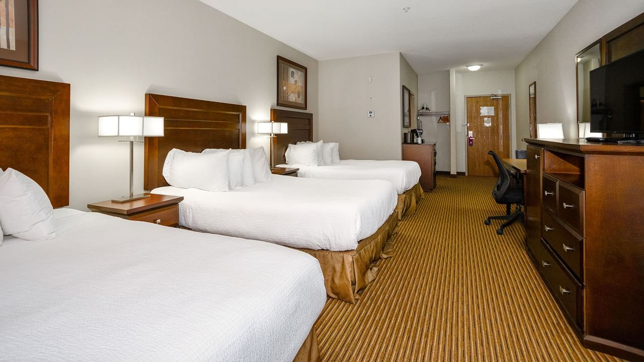 Hotel room with three queen beds, microwave, TV, work desk and coffee machine