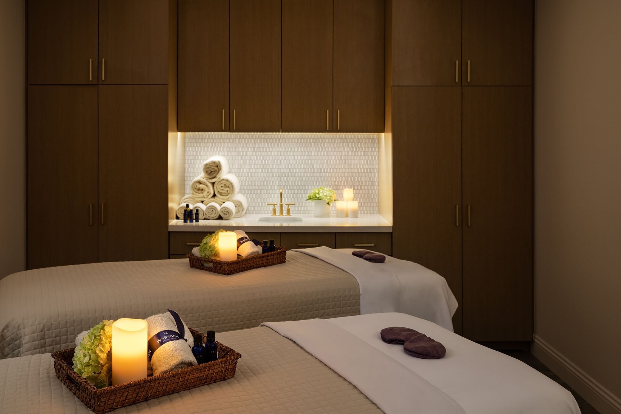 Treatment room with two massage tables, candles, and towels at Le Spa by Warwick Melrose