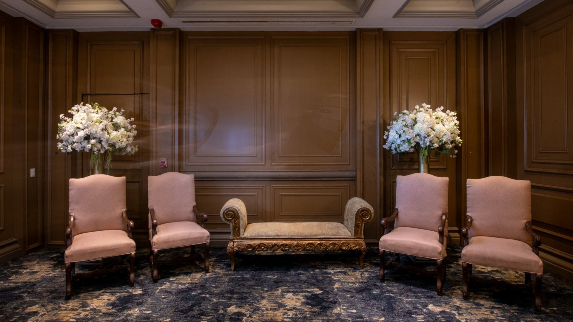Luxurious Salon Marques featuring pink velvet chairs, an ornate bench, and white florals at Quinta Real Monterrey