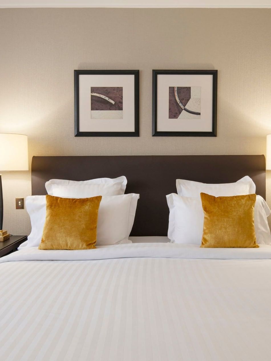 Superior Room features Side tables with lamps by a large bed under two abstract paintings at Warwick Paris Champs Elysées